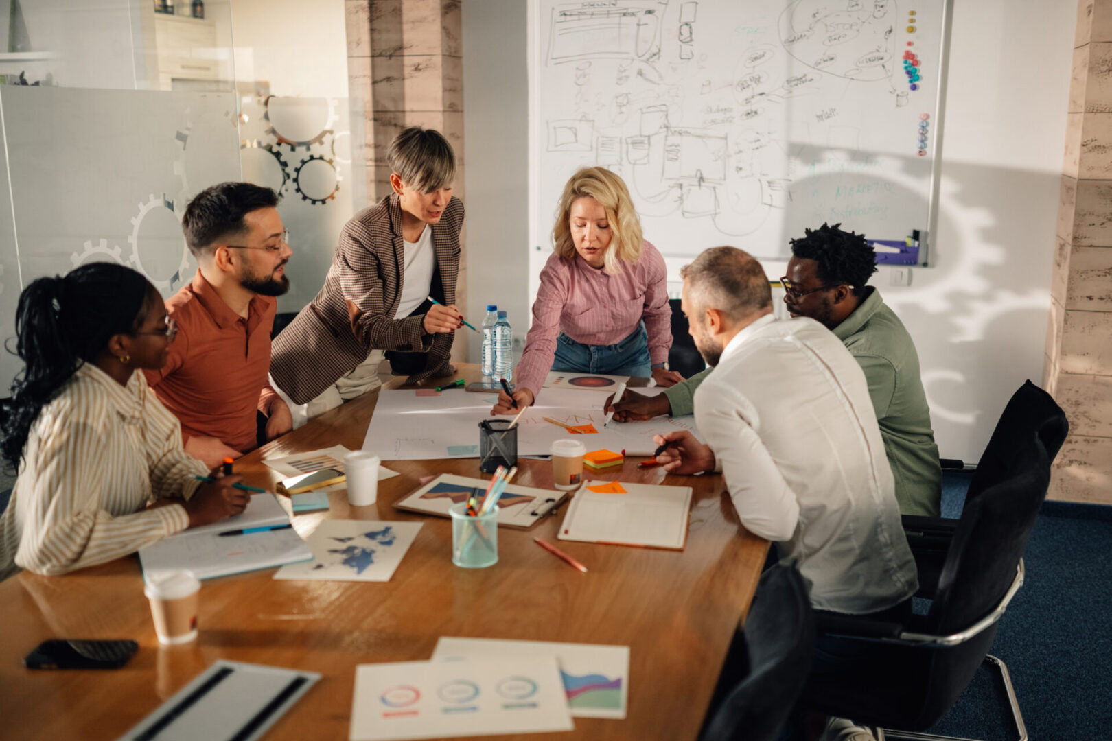 Diverse team of marketing professionals working together on a project in a modern office, analyzing charts and graphs on a large table