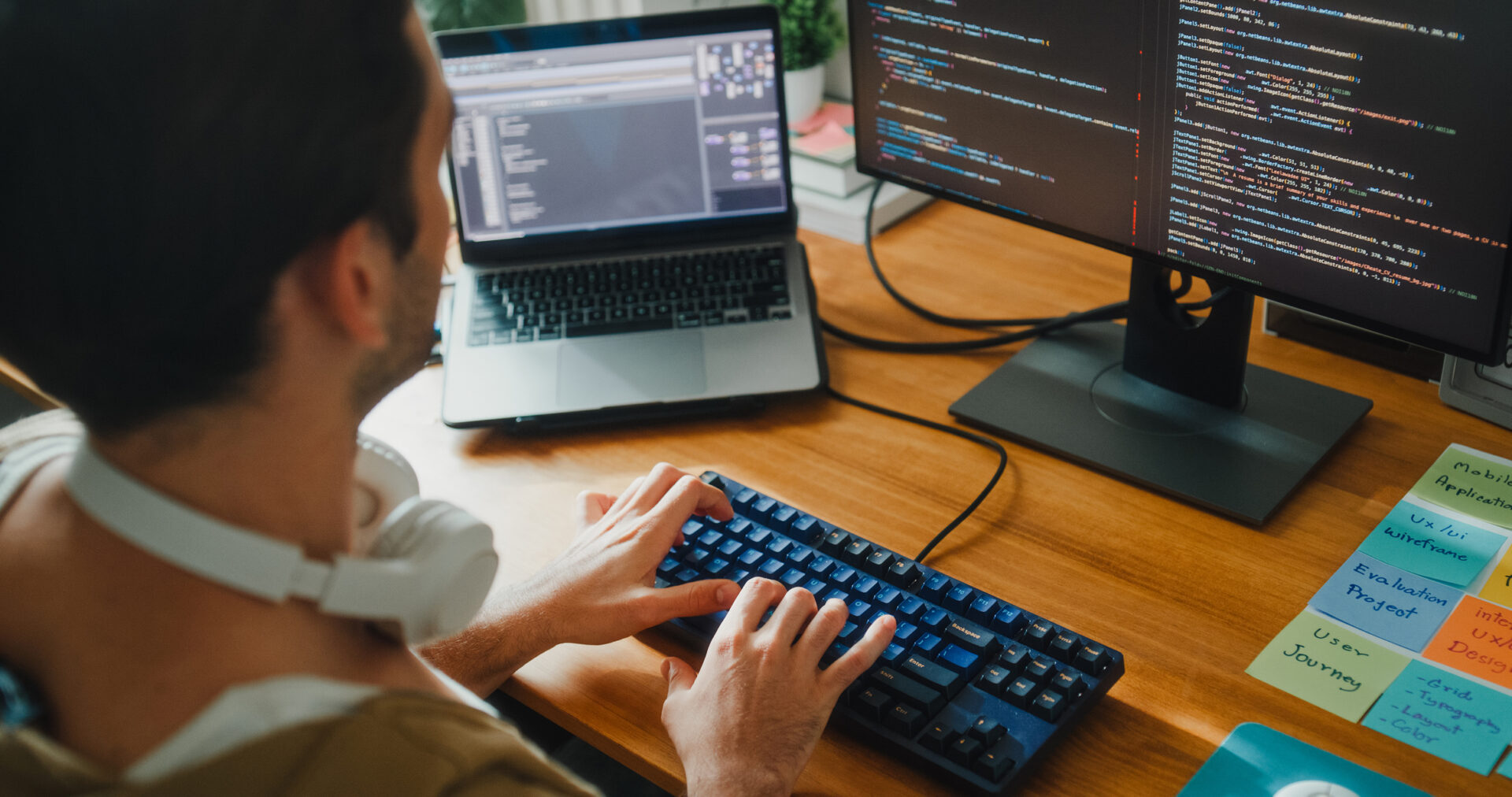 Closeup of young gay computer programmer working on AI prompts web page designs coding user experience on laptop in bedroom at home. Software developer, artificial intelligence programming concept.