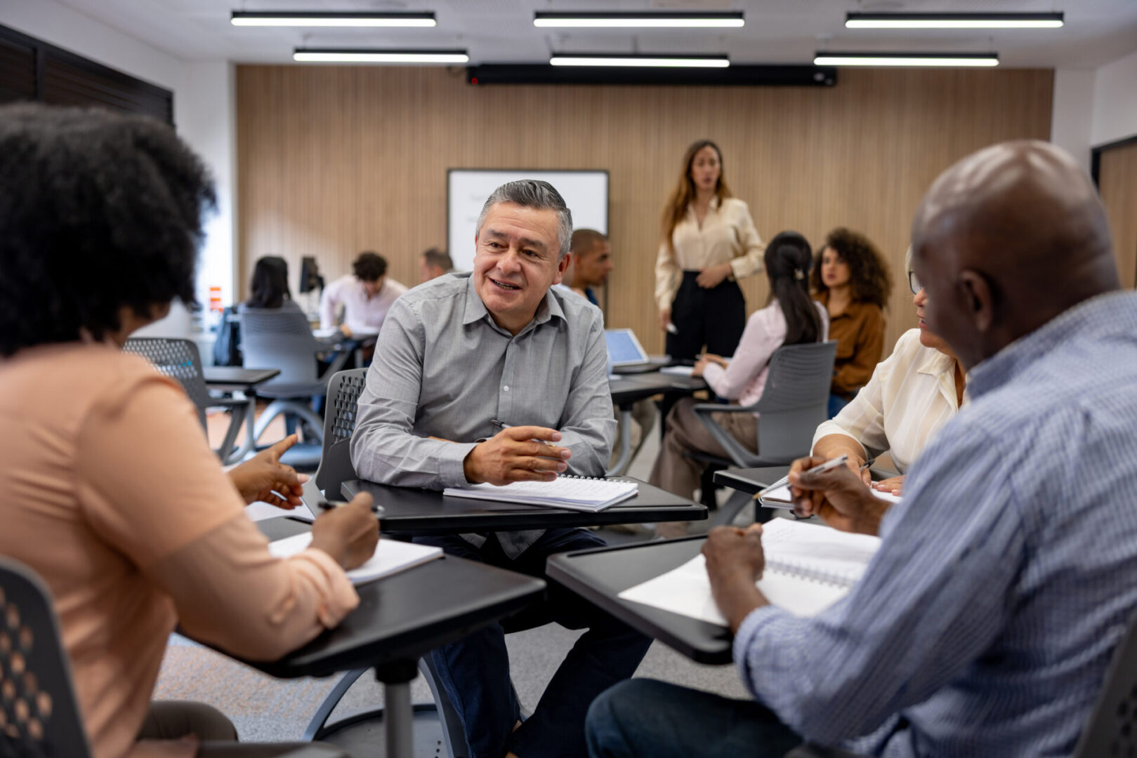 Mature Latin American man going back to school and debating with his classmates - education concepts