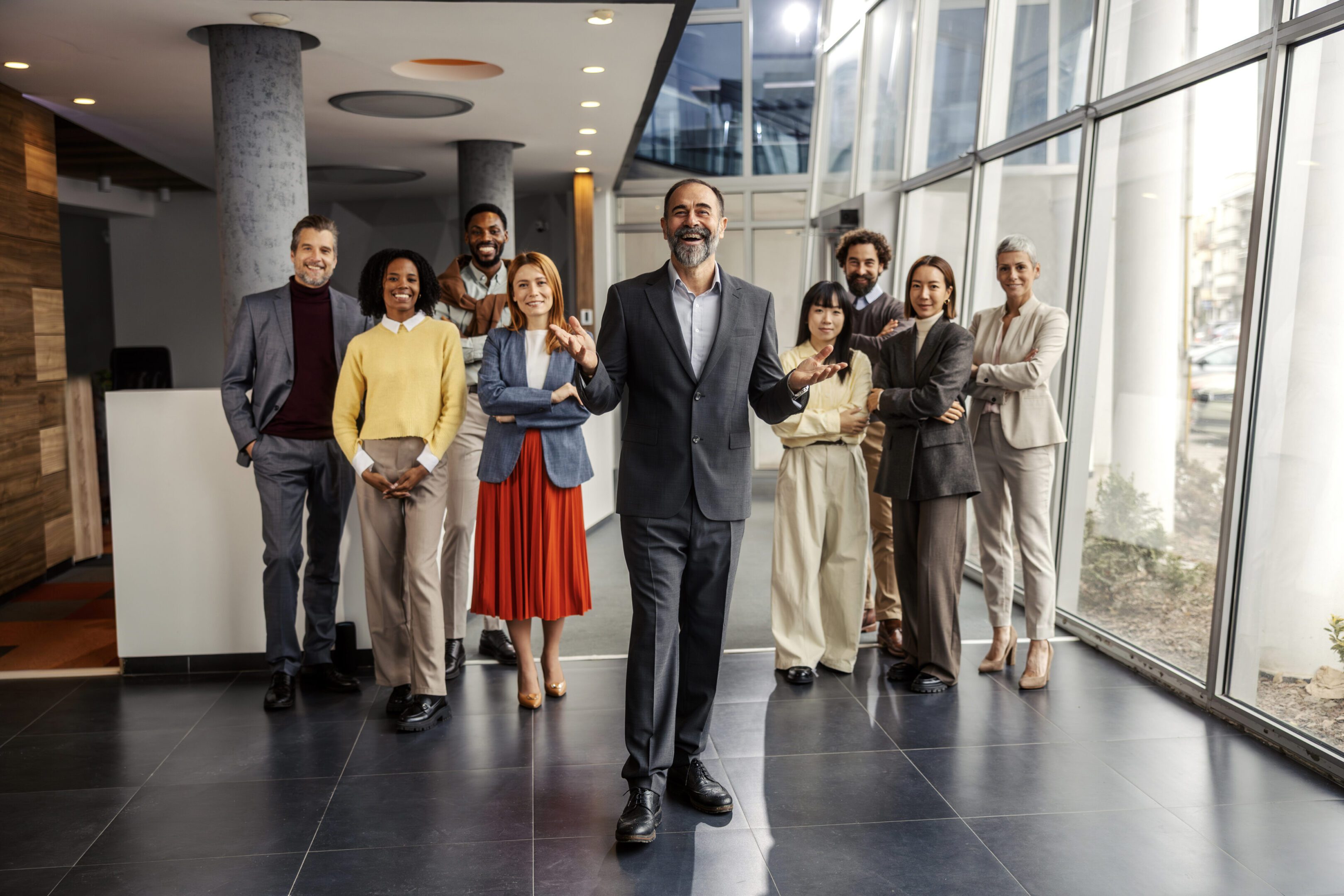 Confident mature adult male manager standing in front of his multi-ethnic business team in a modern office, planning strategies and fostering successful collaboration