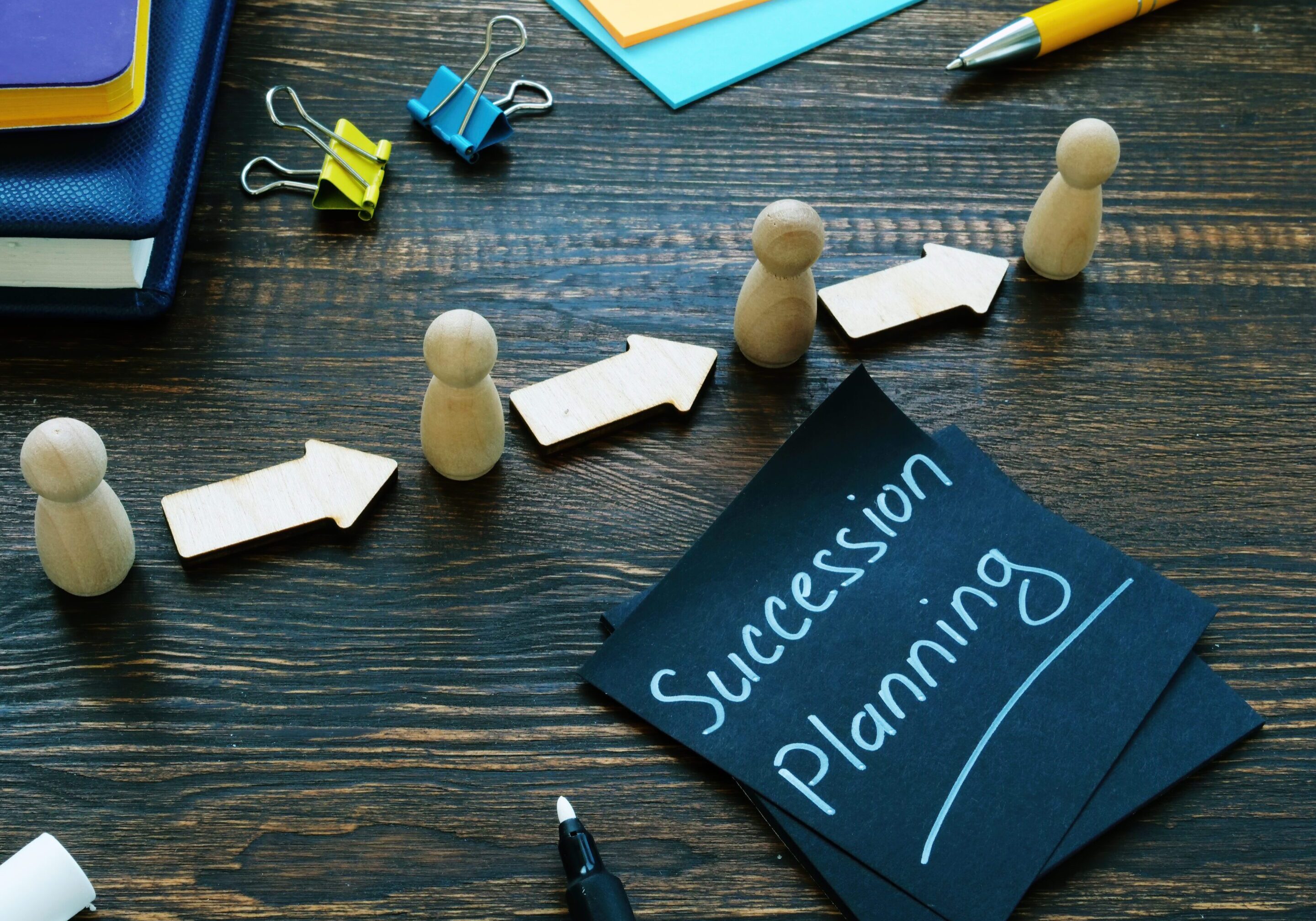 Succession planning sign and figurines with arrows.