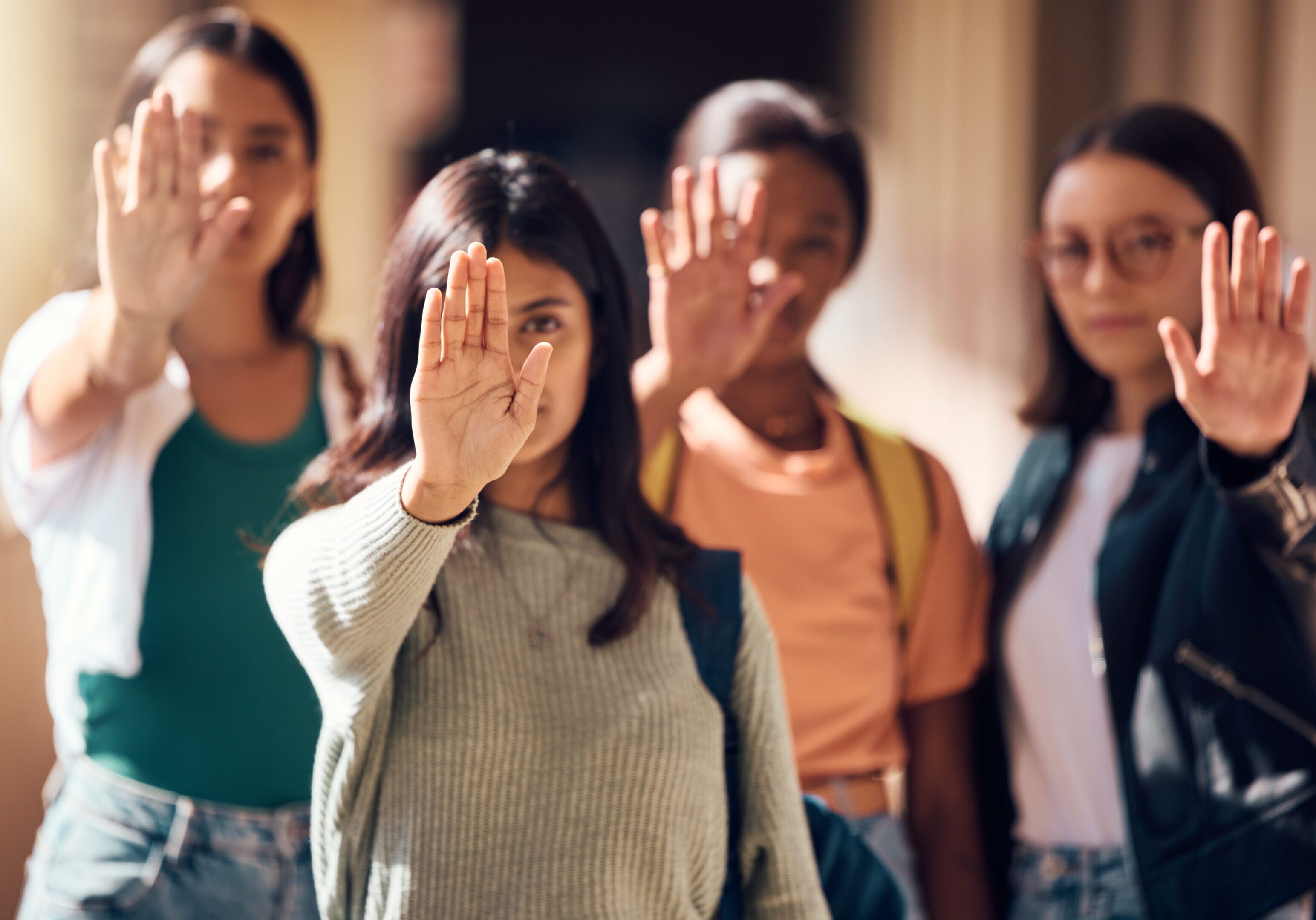Woman, student and hands in stop for protest, enough or  team standing for human rights or women empowerment. Group of female students with raised hand in halt, unity or strike for safe education