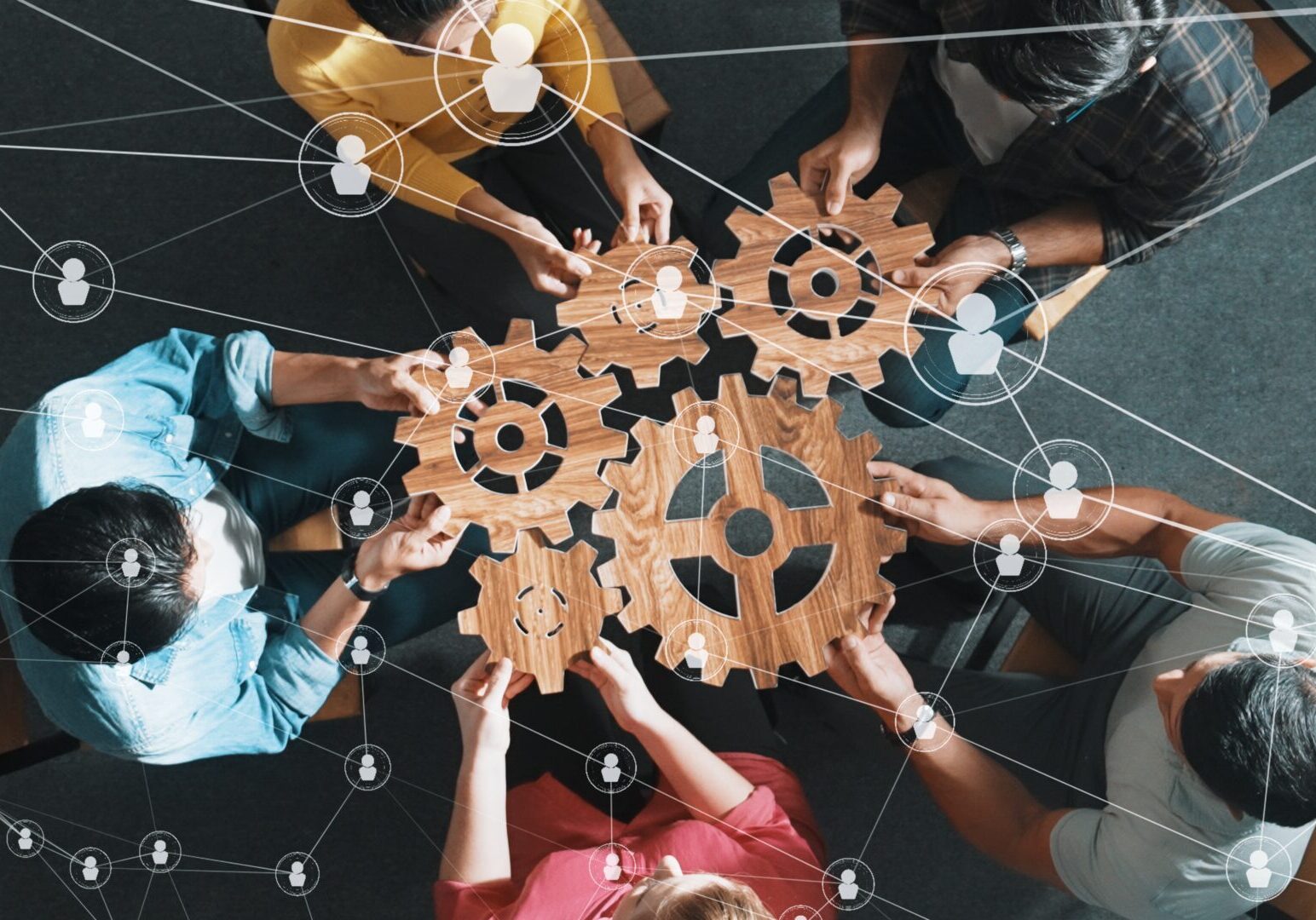 Top view of professional business people joining and gathering wooden gear together. Aerial view of diverse team working together to put or collect cog with network connection holographic. Symposium.