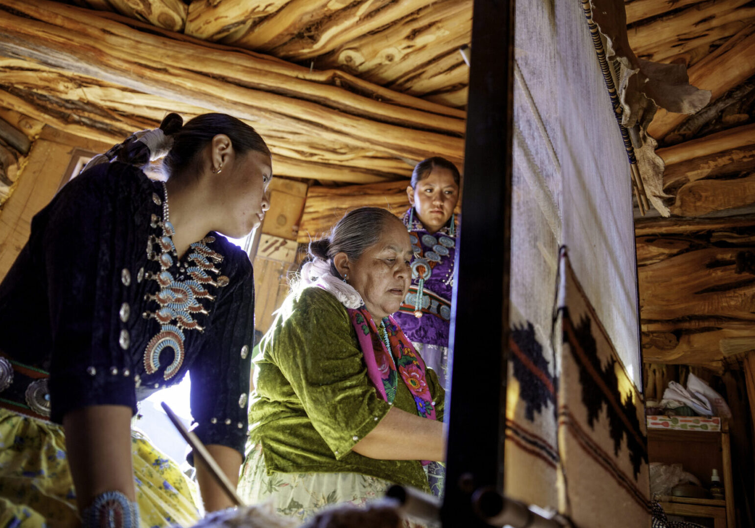 Traditional Elderly Navajo Woman Working to Make an Authentic Blanket on a Loom, Teaching Her Granddaughter and Spending Quality Time in a Traditional Navajo Hogan in Monument Valley Southern Utah, Northern Arizona