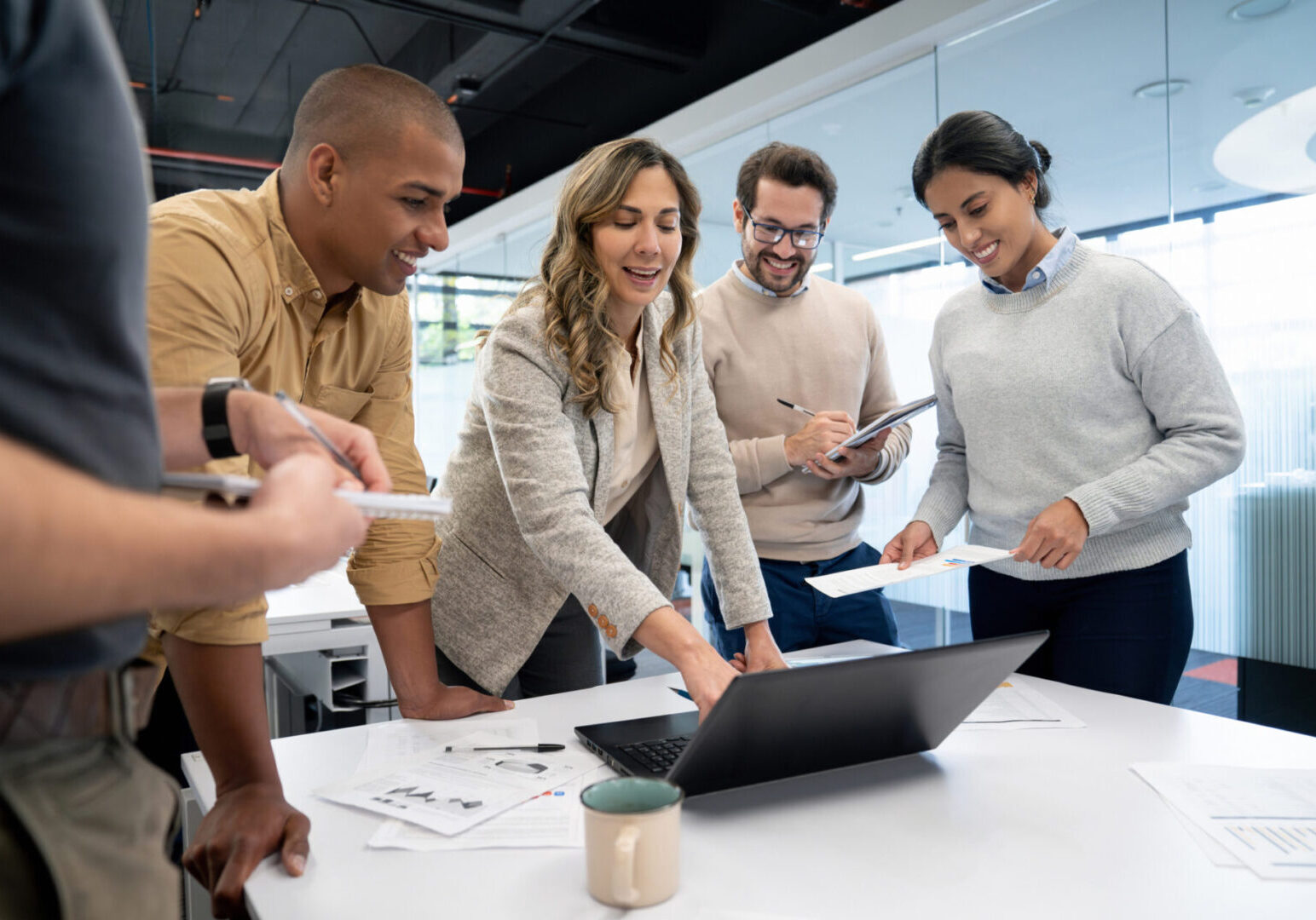 Successful Latin American woman talking to her team in a business meeting at the office and pointing at a laptop