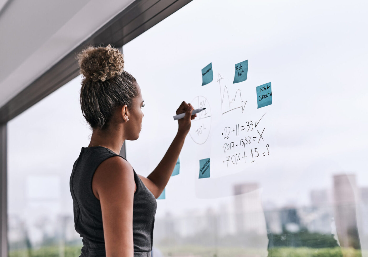 Shot of a young businesswoman writing on a glass wall in an office